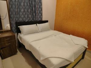 a bed with white sheets and pillows in a room at KOTLAS Highliving Service Apartments in Gachibowli +7 photos