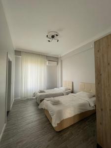 two beds in a room with white walls and wooden floors at Villa akça in Masukiye