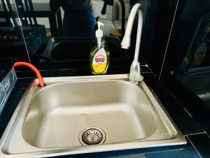 a kitchen sink with a bottle of detergent in it at 1BDM Aptmt Free Wifi,TV, NETFLIX,FRIDGE,KITCHEN-busy area in Dar es Salaam