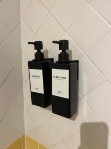 two black bottles of soap sitting on a wall at Tuscia Home Backpackers in Orte