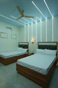 two beds in a room with a ceiling fan at Deep Palace Inn in Mathura