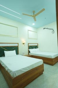 two beds in a bedroom with a ceiling at Deep Palace Inn in Mathura