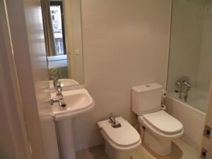 a white bathroom with a toilet and a sink at Apartaments Sant Jordi Fontanella in Barcelona