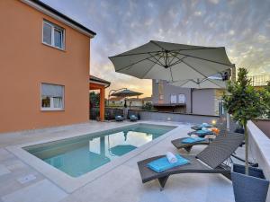 プーラにあるVilla in Pula with Pool & Parasolの椅子2脚と傘が備わったプール