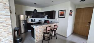 a kitchen with a bar with stools and a refrigerator at The Sky View in San Salvador