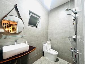 a bathroom with a sink and a toilet and a mirror at SIII Vũng Tàu Garden coffee & homestay in Vung Tau