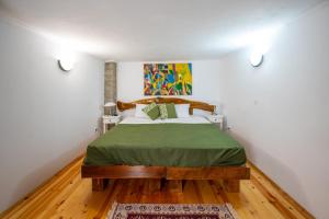 ein Schlafzimmer mit einem Bett mit einer grünen Bettdecke in der Unterkunft Къща за гости Приказка in Klisura