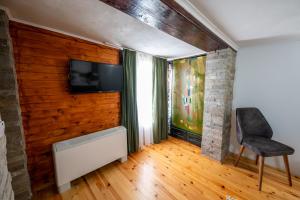 Zimmer mit einer Wand, einem TV und einem Stuhl in der Unterkunft Къща за гости Приказка in Klisura