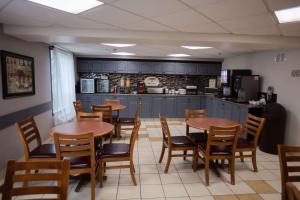 a restaurant with tables and chairs and a kitchen at Super 8 by Wyndham Whitecourt in Whitecourt