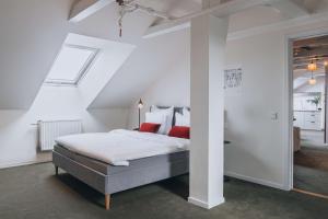 a white bedroom with a bed with red pillows at Story Hotel Riddargatan, part of JdV by Hyatt in Stockholm