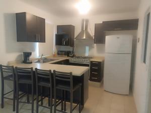 a kitchen with a white refrigerator and a table with chairs at Casa Tezal Alberca in Cabo San Lucas
