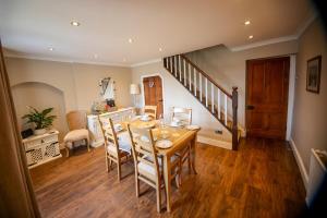 una sala da pranzo con tavolo, sedie e scala di Mill Cottage a Clitheroe