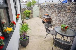 un patio con tavolo e sedie e un muro di pietra di Mill Cottage a Clitheroe