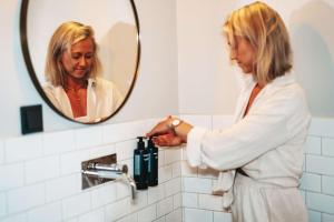 a woman standing in a bathroom looking at herself in the mirror at Story Hotel Riddargatan, part of JdV by Hyatt in Stockholm