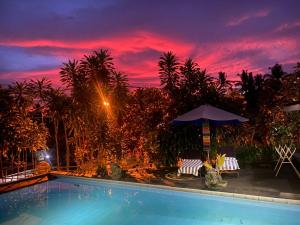 a swimming pool at night with a sunset at SunwuKong Guest House in Ubud +35 photos