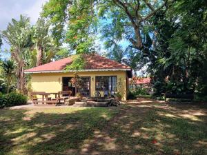 a small yellow house with a picnic table in a yard at Marula Gardens in Mtubatuba