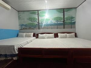 2 letti in una camera con un dipinto sul muro di Nhà Nghỉ Mấy Kiên a Phan Thiet
