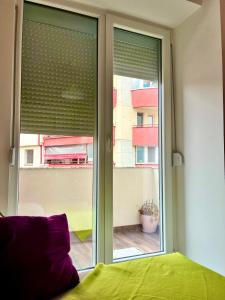 a bedroom with a window with a green bed and a view at Mor Maison Skopje City-Center FEW FREE PRIVATE PARKING in Skopje