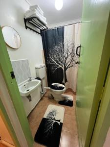 a bathroom with a toilet and a shower with a tree shower curtain at Pequeno Cielo Staycation in Nairobi