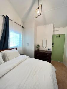 a bedroom with a large white bed and a mirror at Pequeno Cielo Staycation in Nairobi