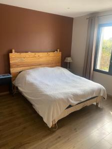 a bedroom with a bed with a wooden headboard and a window at Beautiful architectural villa 10 pool beds in Laure-Minervois