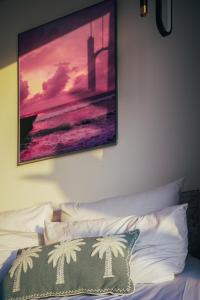 une peinture accrochée au-dessus d'un lit avec un oreiller dans l'établissement Wander Havens, à Canggu