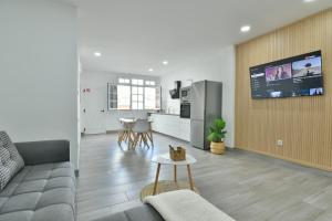 Una sala de estar con un sofá y un televisor en una pared. en Suite Orquídea, en Cruce de Arinaga