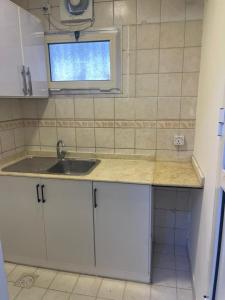 a kitchen with white cabinets and a sink and a window at وحدات سكنية مفروشة in Jeddah