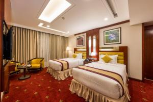 a hotel room with two beds and a television at Grand Palace Hotel & Resort Dhaka in Dhaka