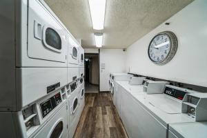 ホノルルにあるChic DT Honolulu Executive Condo condoの白い洗濯機と壁に時計が掛かっている洗濯室