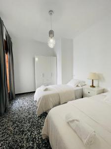 een witte kamer met 2 bedden en een lamp bij Charment appartement a vinaros in Vinarós