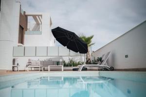 Laguna Beach Villa Veintidos في توريفايجا: مسبح مع مظله بجانب المنزل