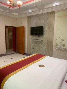a bedroom with a large bed and a flat screen tv at فندق فيفاء الفاخر in Fayfāʼ