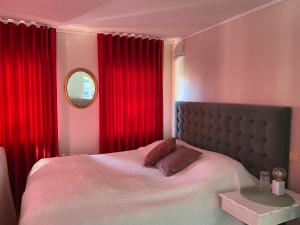 a bedroom with a bed with red curtains and a mirror at Grand 5 Room Villa in Kallfors, Järna, Stockholm near Forest, the Baltic Sea and a Golf course - a whole house no shared rooms in Järna
