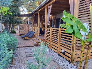 a house with a wooden porch with a chair on a deck at Ventura mobile home in Biograd na Moru