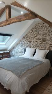 a bed in a room with a stone wall at Le repère champêtre in Tréméreuc