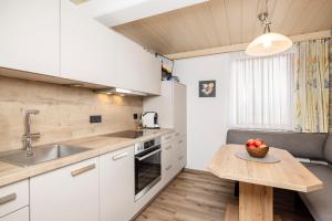kuchnia z białymi szafkami i drewnianym stołem w obiekcie Appartement Summerer Peter w Mayrhofen