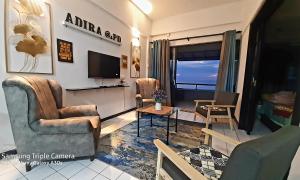 a living room with two chairs and a flat screen tv at Adira Corus Paradise Seaview Family Suite in Port Dickson