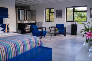 a bedroom with a bed and two blue chairs at Dreamhouse Guest House in Hout Bay