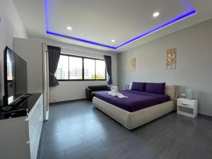 een slaapkamer met een paars bed en een flatscreen-tv bij PATTAYA POOL VILLA 427 nearby WALKING STREET in Pattaya South