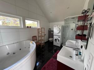 a bathroom with a tub and a sink and a washing machine at Hytta in Bømlo +8 photos