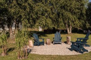three blue chairs sitting in the grass under a tree at Domki Podniebo in Jarosławiec