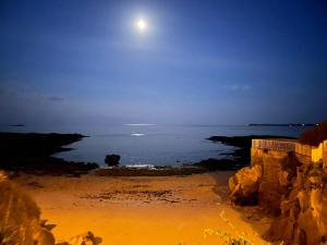 una vista de la playa por la noche con la luna en T2 37 M2 les pieds dans l'eau, en Ploemeur