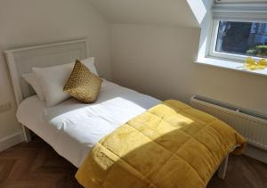 a bedroom with a white bed with a yellow blanket at Penthouse apartment with stunning sea views in Penmaen-mawr