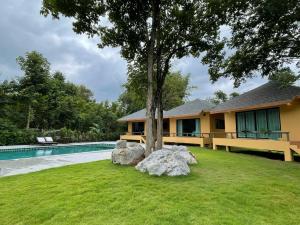 a house with a tree next to a swimming pool at Jindarin Villas in Ban Nong Sarai (1)