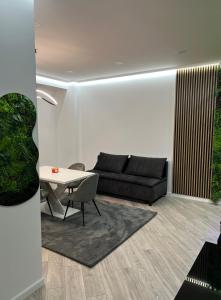 a living room with a black couch and a table at Sky Apartment in Rădăuţi
