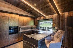 una cucina con pareti in legno e bancone con sedie di Luxury Chalet Tre Cime mit Privat Spa & Pool a Sesto