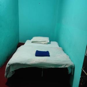 un piccolo letto in una camera con parete blu di Myagdi Devisthan Guest House And Bhanchha Ghar a Pokhara