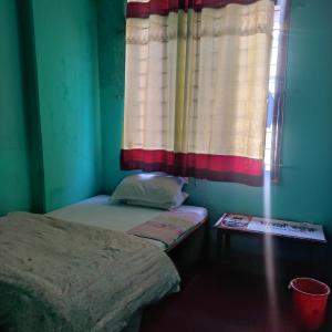 una piccola stanza con un letto e una finestra di Myagdi Devisthan Guest House And Bhanchha Ghar a Pokhara