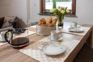 a table with plates and cups and a basket of bread at FeWo Severin in Bottrop